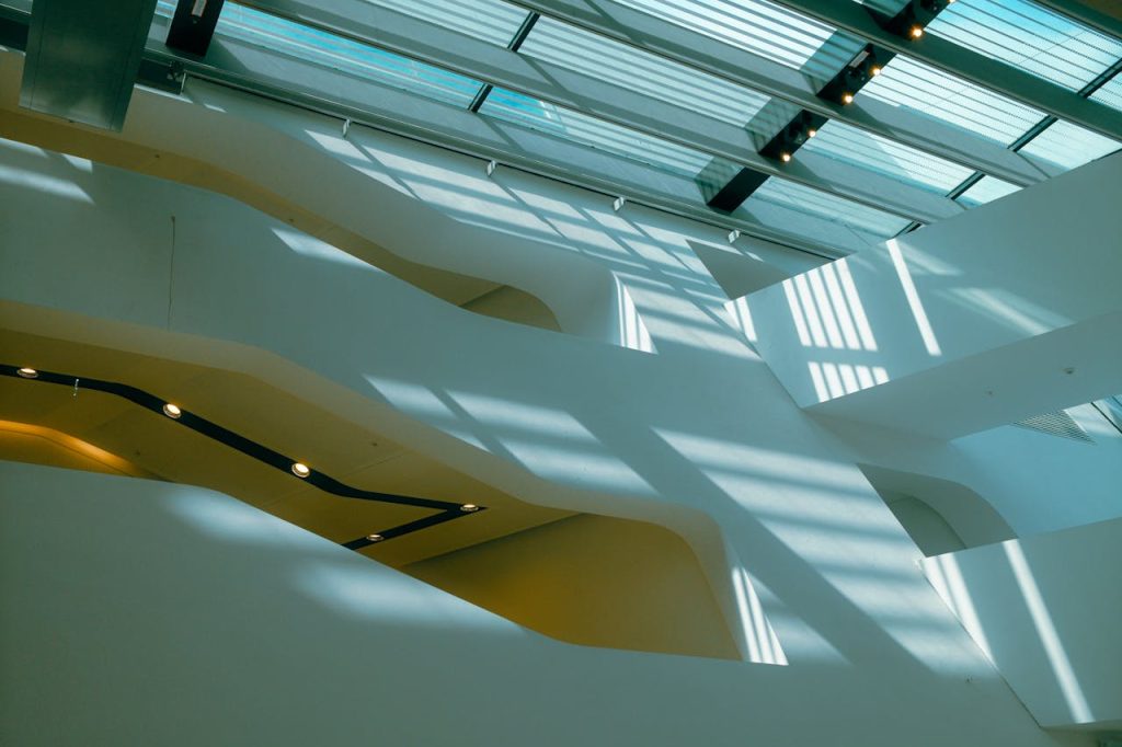 Abstract view of modern architecture with sunlight casting shadows through glass roof.