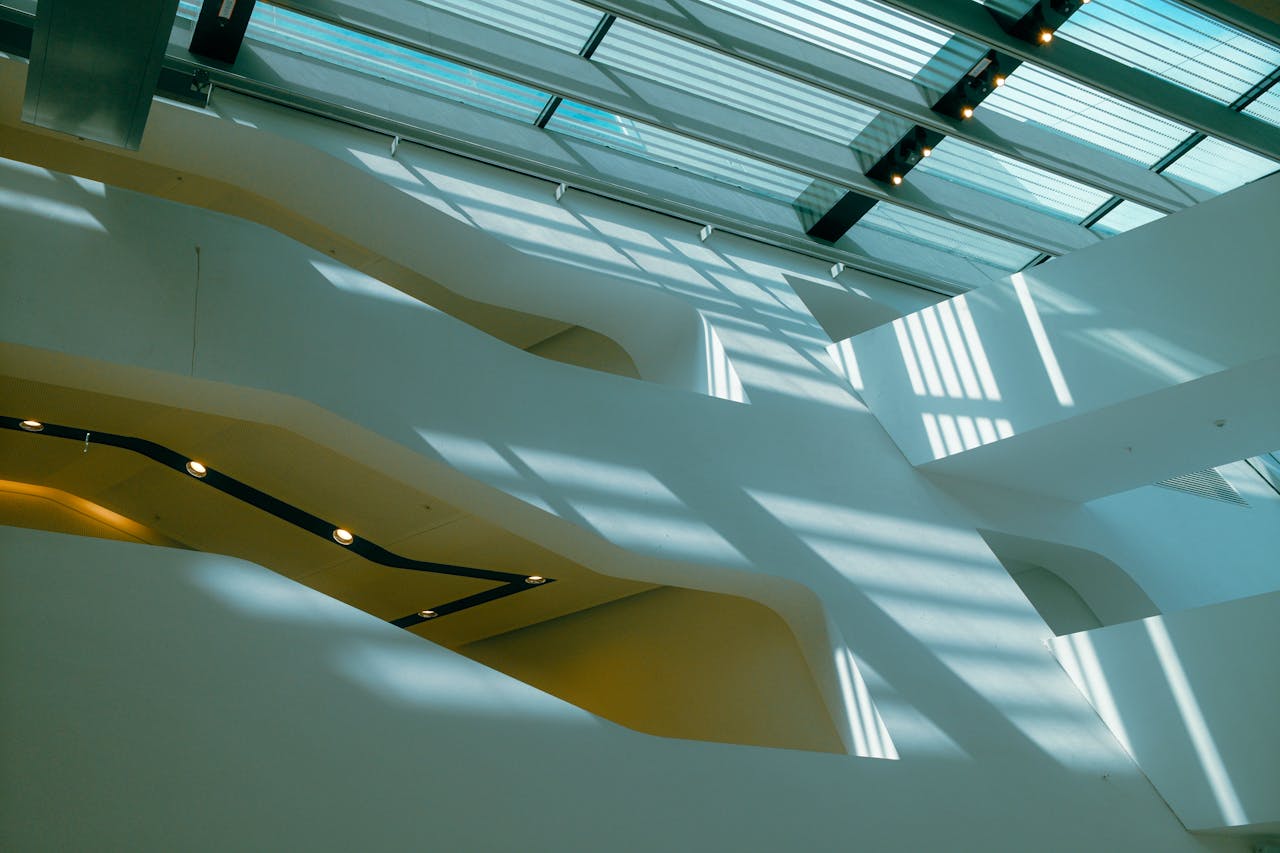 Abstract view of modern architecture with sunlight casting shadows through glass roof.